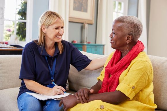 A woman is sitting on a couch talking to an older woman.