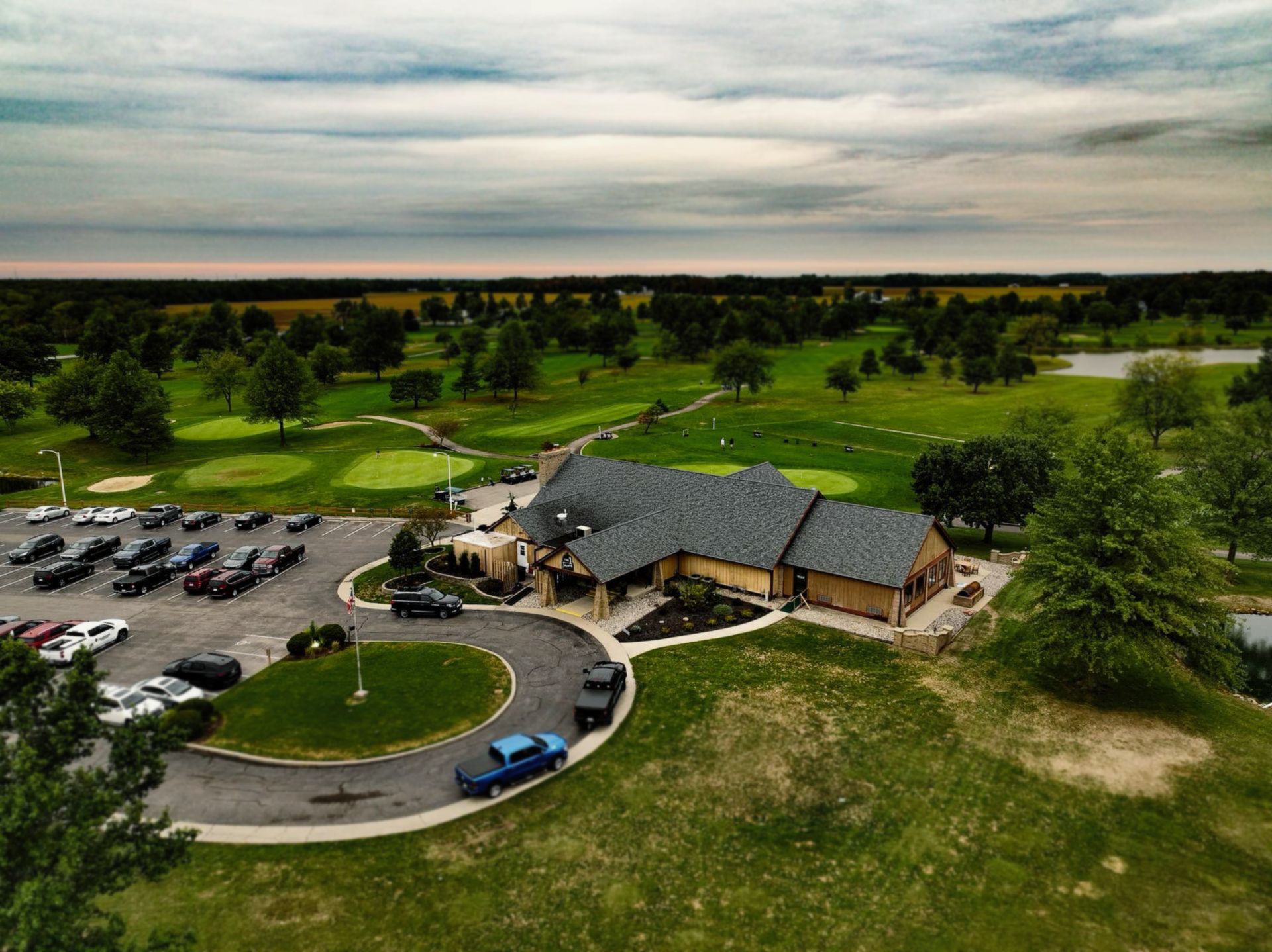 An aerial view of a golf course with a clubhouse and parking lot.