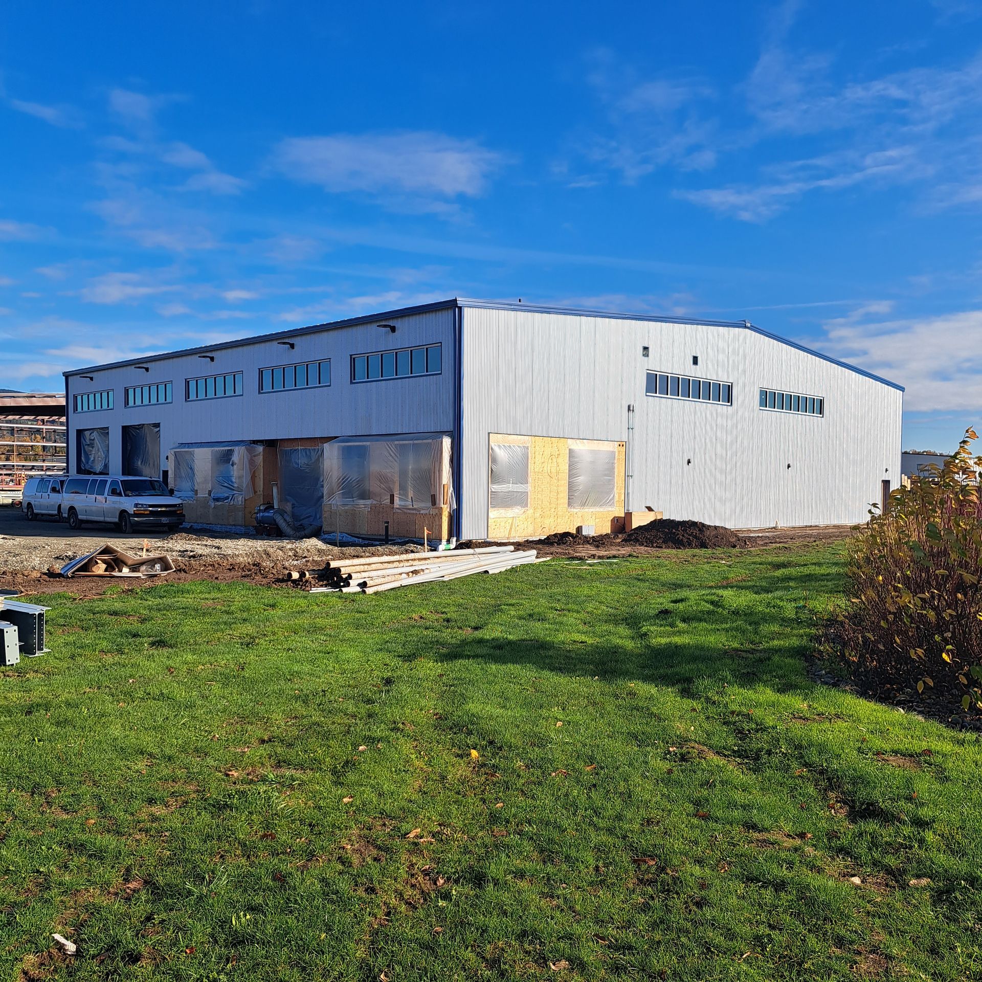 A large white building is sitting in the middle of a grassy field.