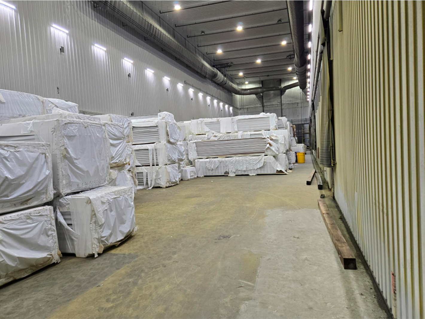 A large warehouse filled with lots of boxes wrapped in plastic.