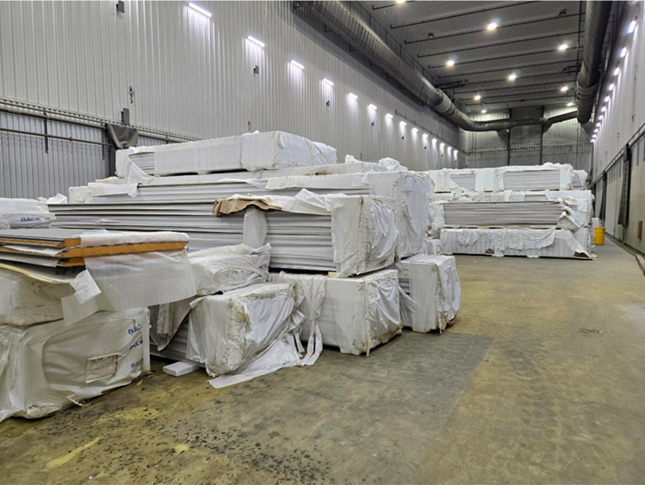 A large warehouse filled with lots of wrapped pieces of wood.
