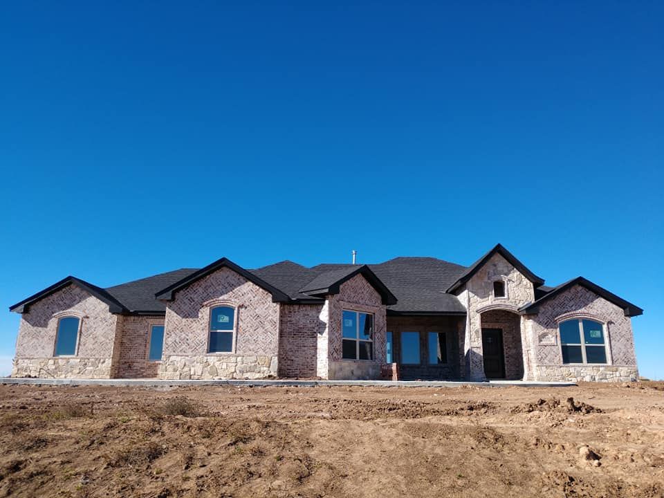 New brick house under construction against a clear blue sky.
