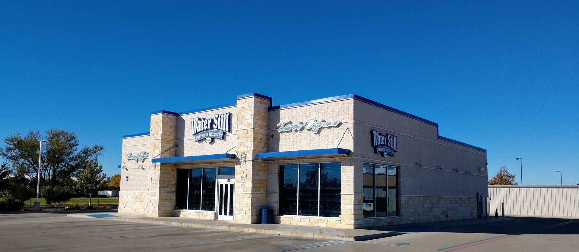 Building with blue trim and signage against a clear, blue sky.