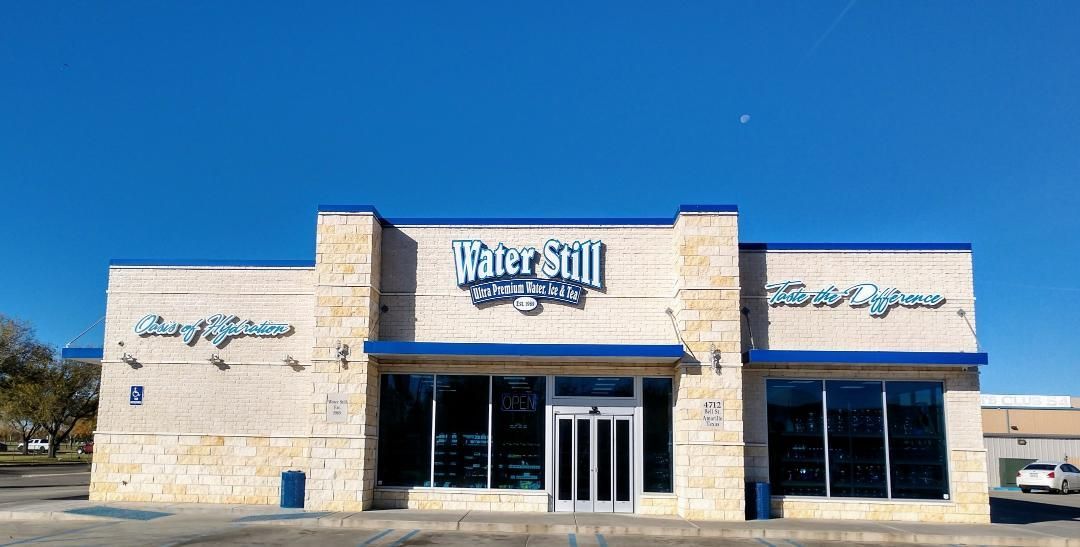 Water Still Company storefront with blue accents, against a clear blue sky.