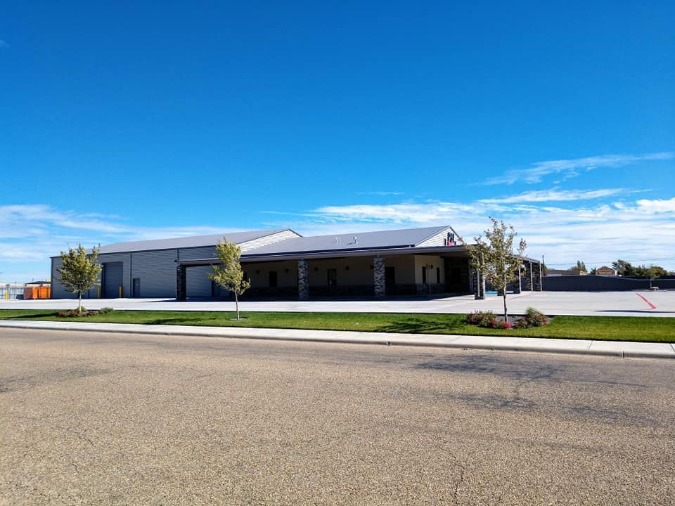 A light grey building with a dark grey roof against a blue sky. 