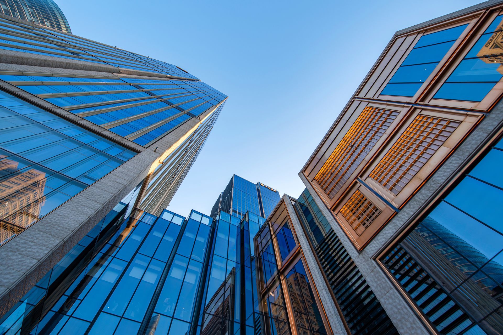 Low-angle view of modern skyscrapers with blue glass windows against a clear sky.