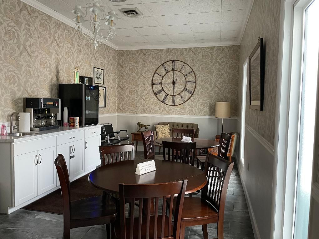 Cafe interior with a coffee bar, tables, chairs, and a large wall clock.