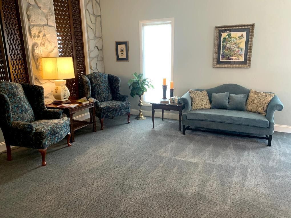 Living room with blue furniture, art, table lamps, and neutral gray carpet.