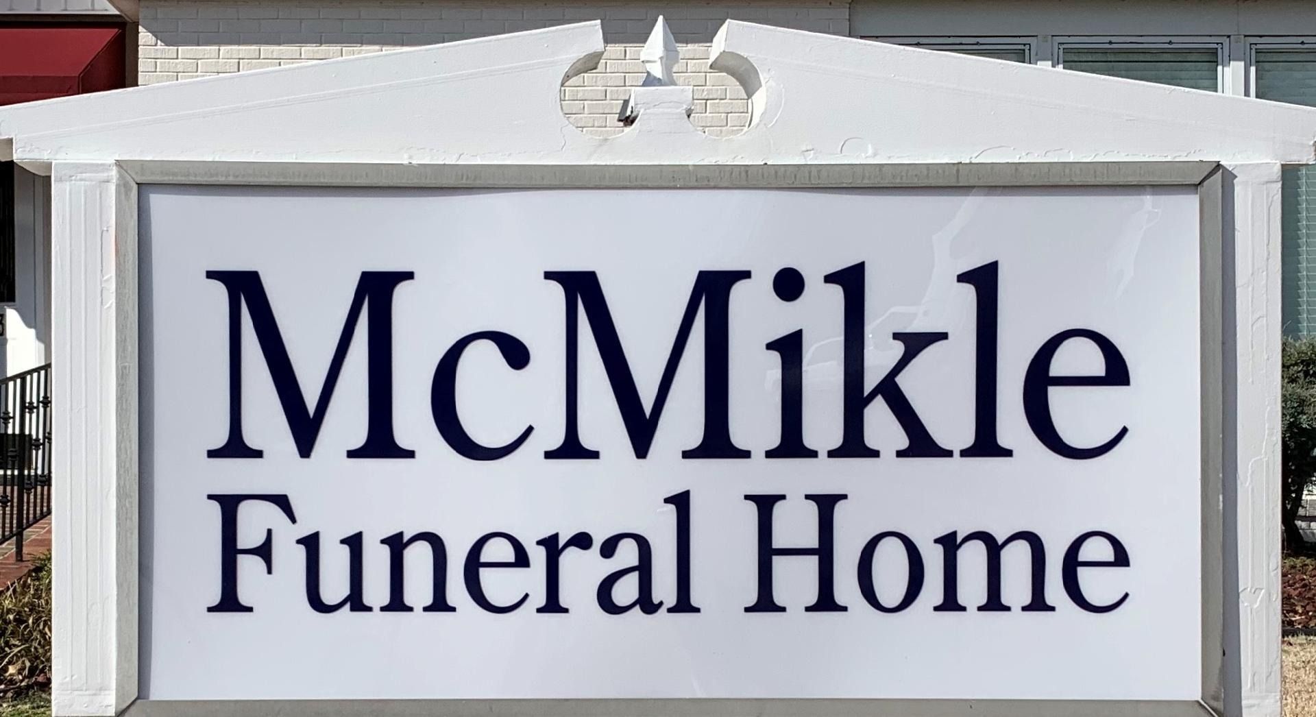 Sign for McMikle Funeral Home in white frame with dark blue text.