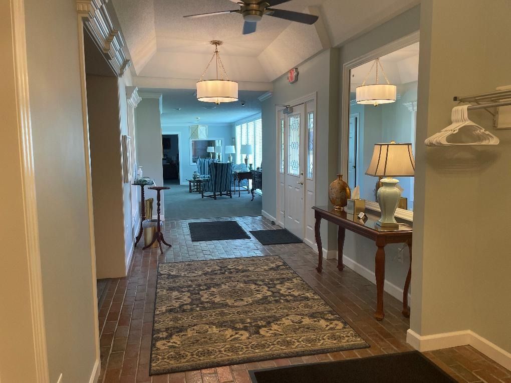 Hallway with rug, lamps, console table, and two hanging light fixtures.