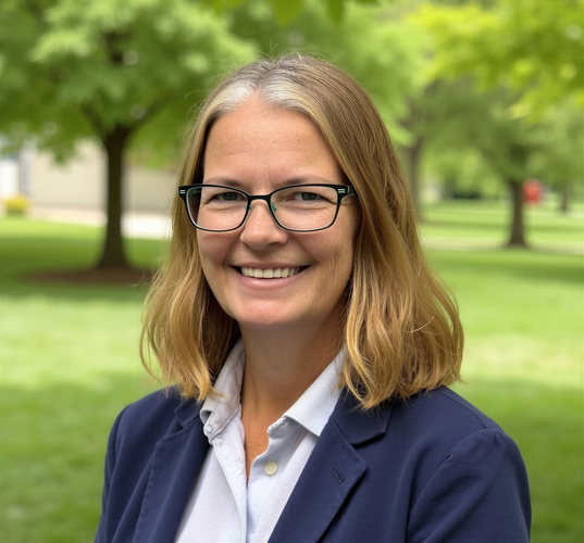 Karen Ryk in glasses and a navy blazer outdoors in a green park