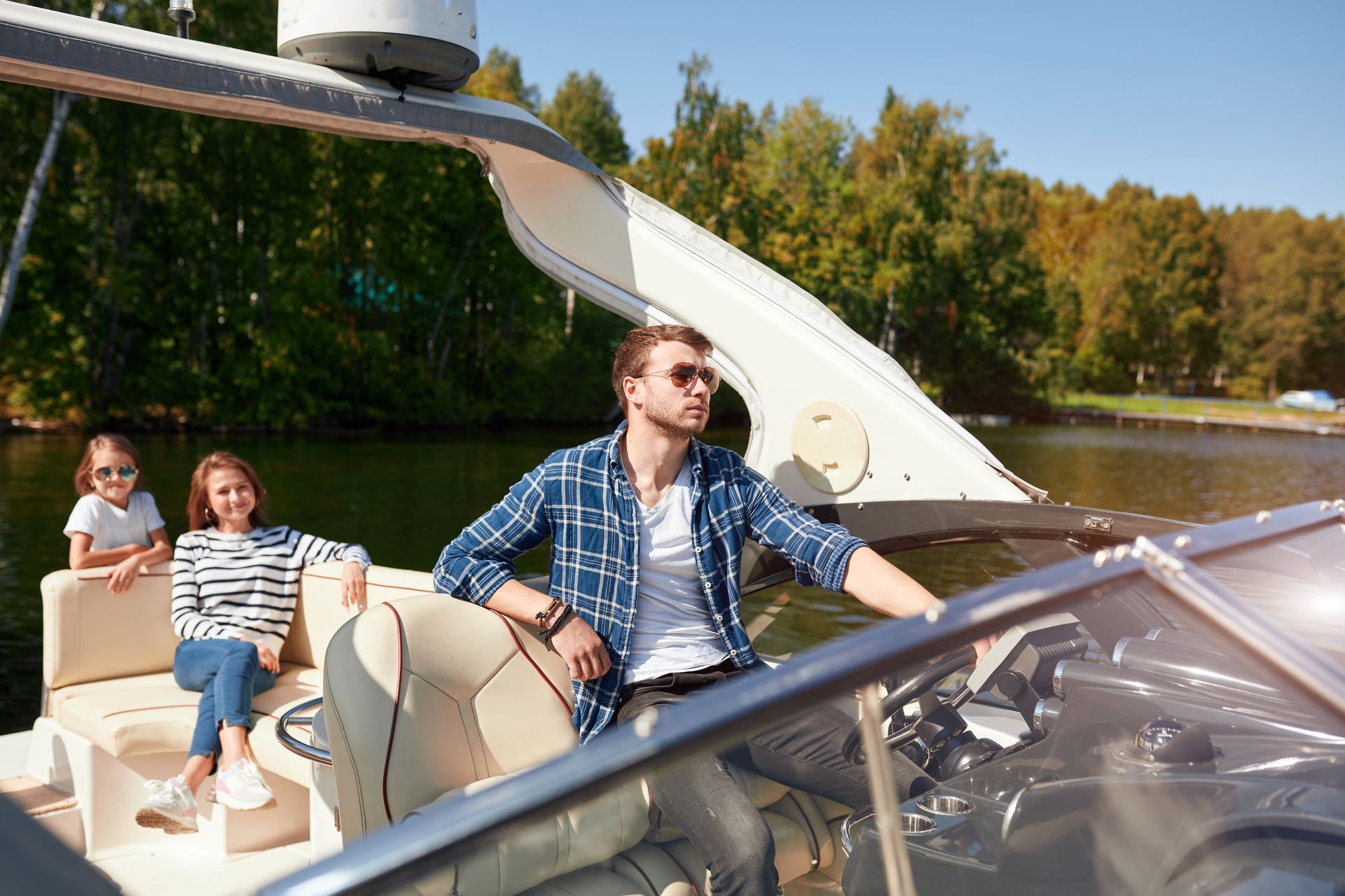 Three people relax on a boat cruising on a sunny lake