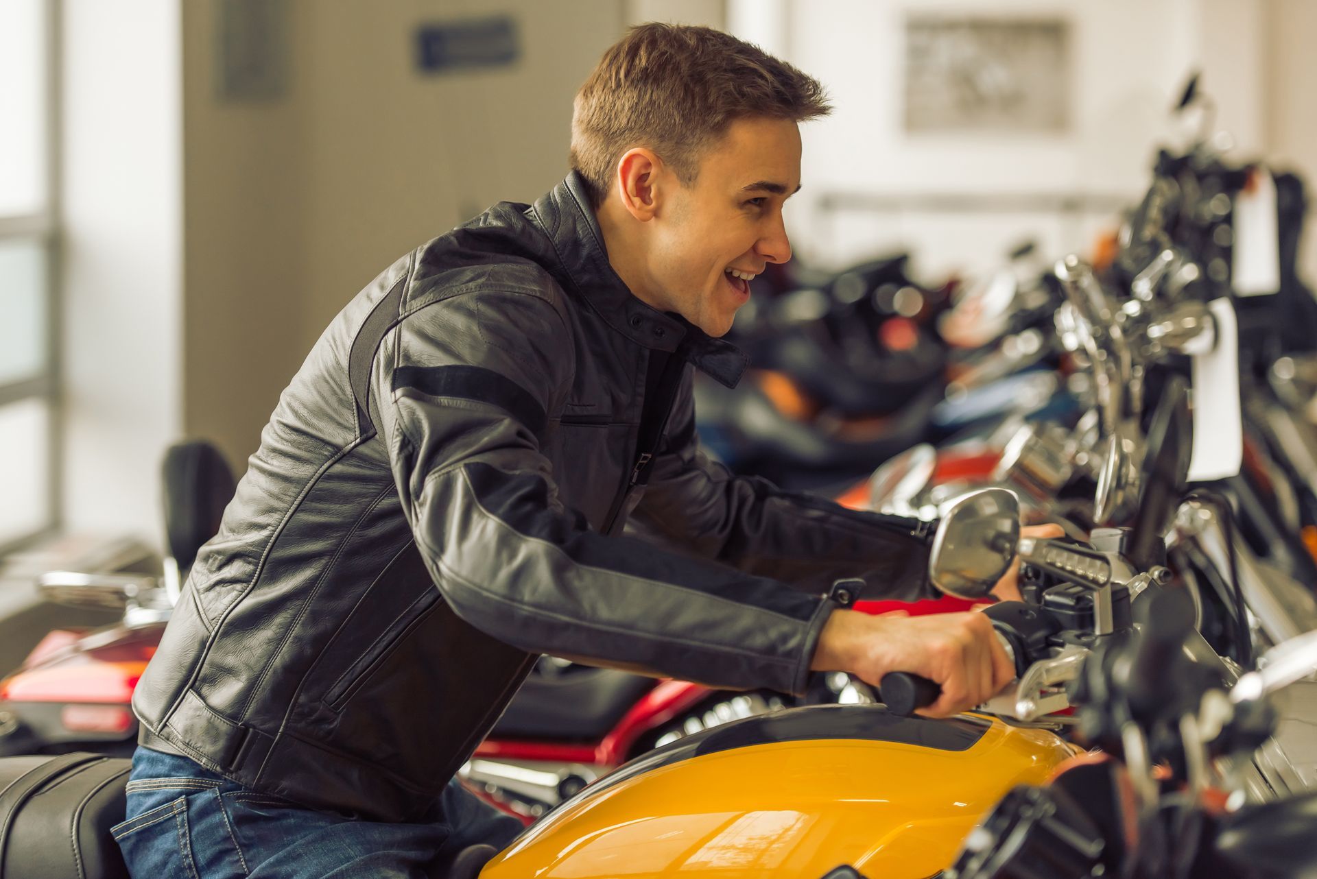 Man smiling while sitting on a yellow motorcycle in a showroom