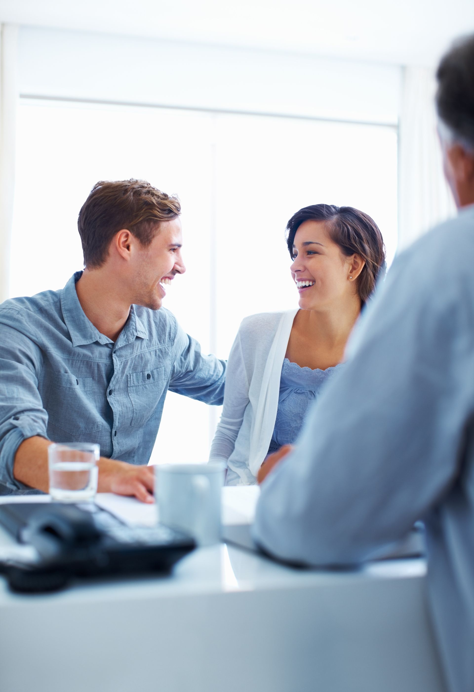 Two coworkers smiling and talking in a bright office meeting room