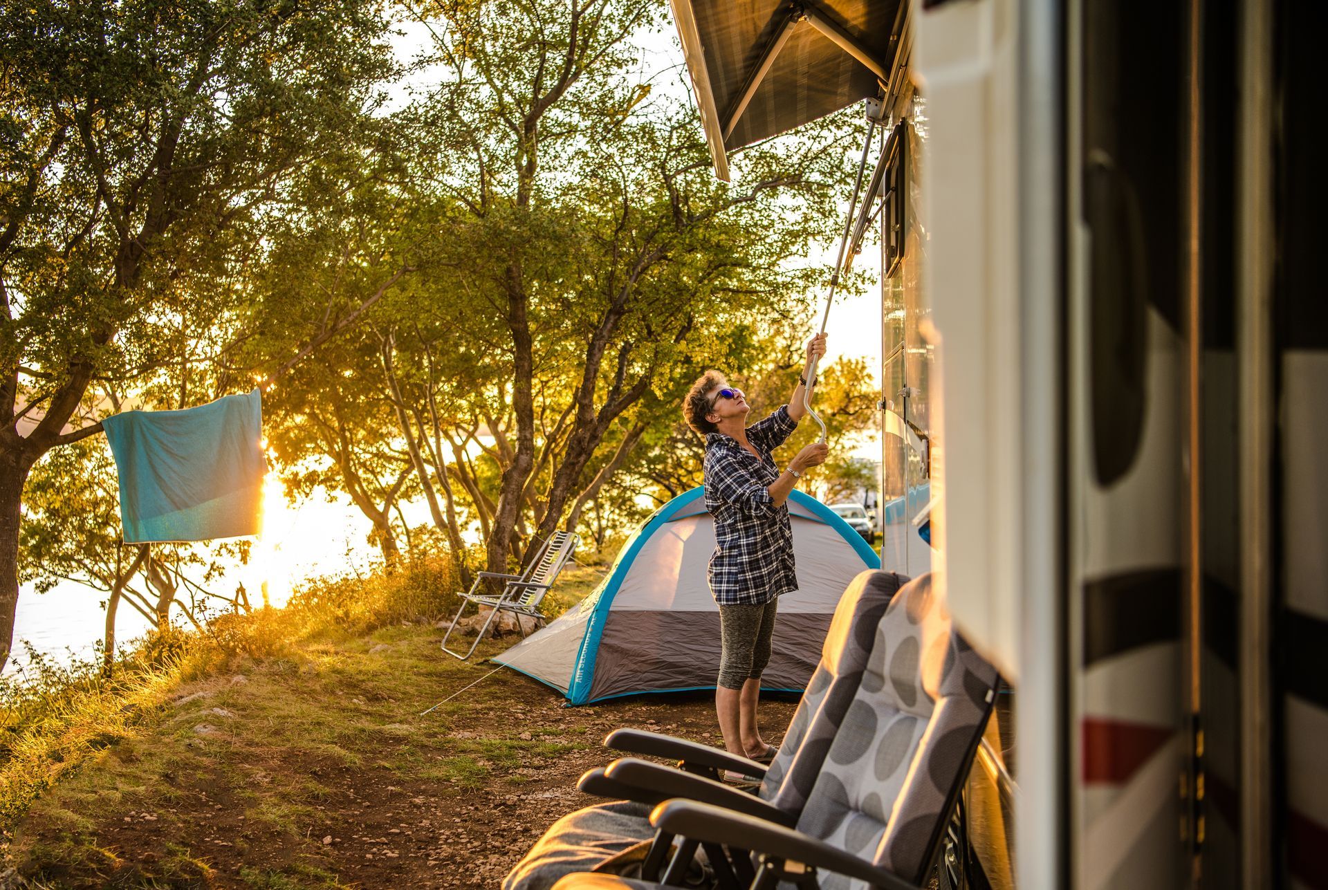 Person hanging laundry beside a tent at a campsite during sunset