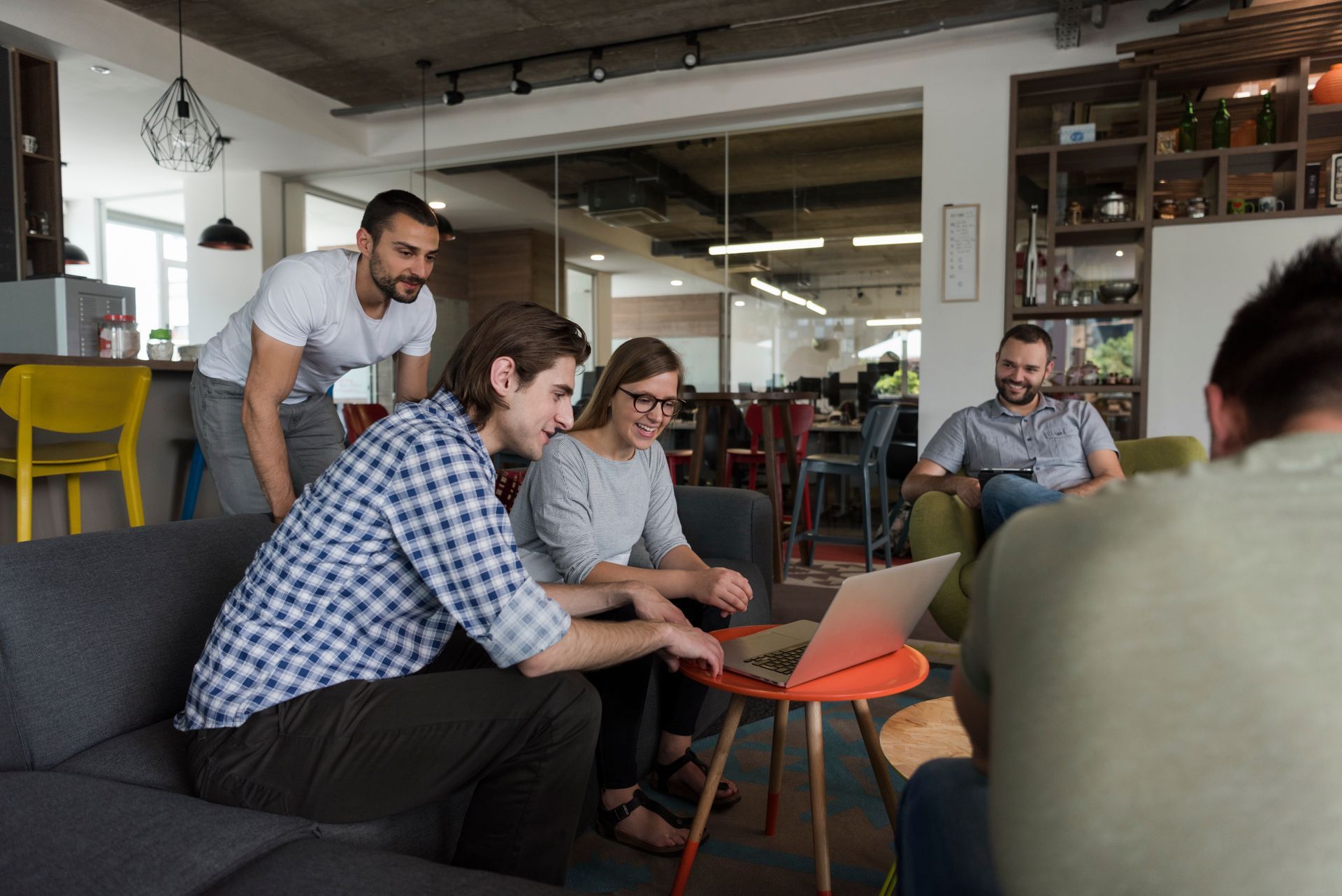 People collaborating around a laptop in a modern office lounge
