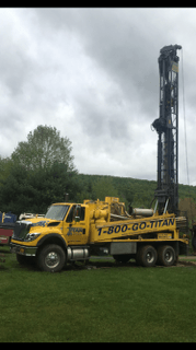 Yellow Titan drilling rig on a cloudy day, on grass, with the phone number 1-800-GO-TITAN visible.