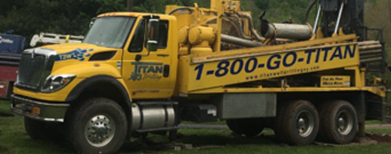 Yellow Titan drilling rig truck with “1-800-GO-TITAN” on the side.