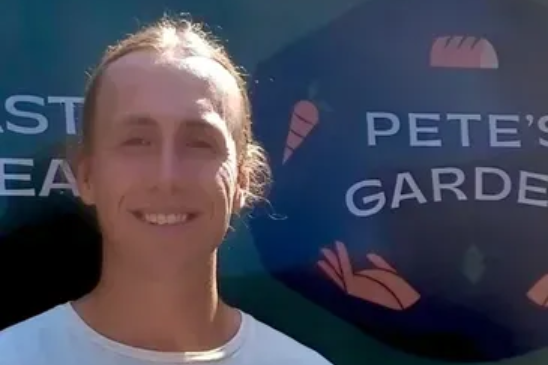 A person smiling in front of a blue 