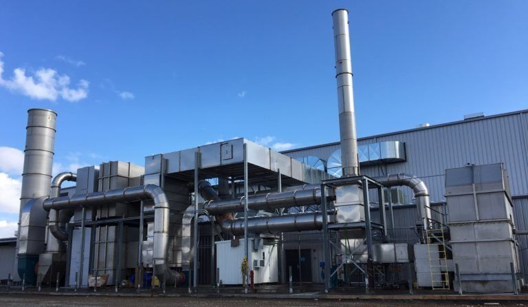 A large industrial building with a lot of pipes and smoke stacks.