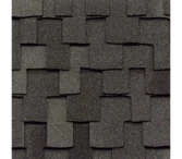 A close-up view of dark gray architectural roofing shingles with a textured, layered, and overlapping design.