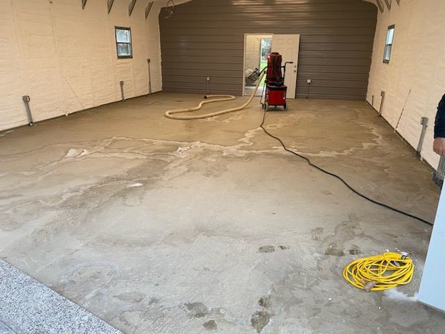 A man is standing in a garage with a vacuum cleaner on the floor.