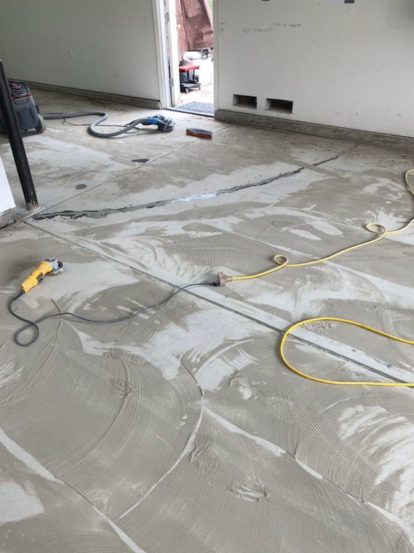 A concrete floor with a yellow cord and a drill on it.