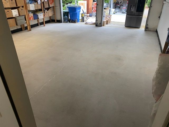 A room with a concrete floor and a refrigerator in it.