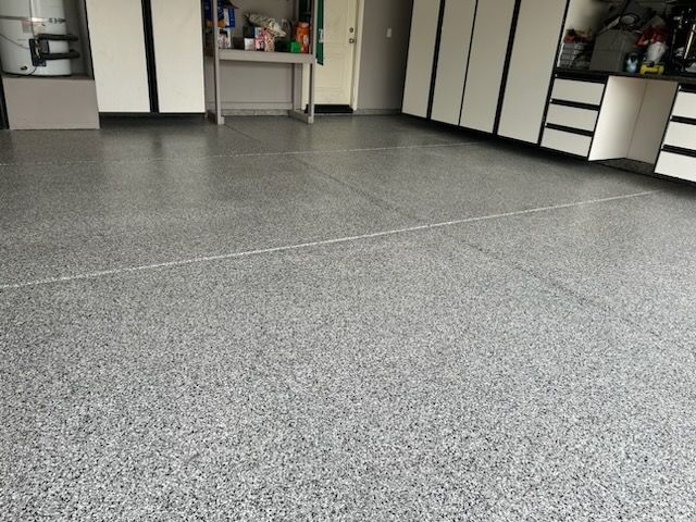 A garage with a gray floor and white cabinets
