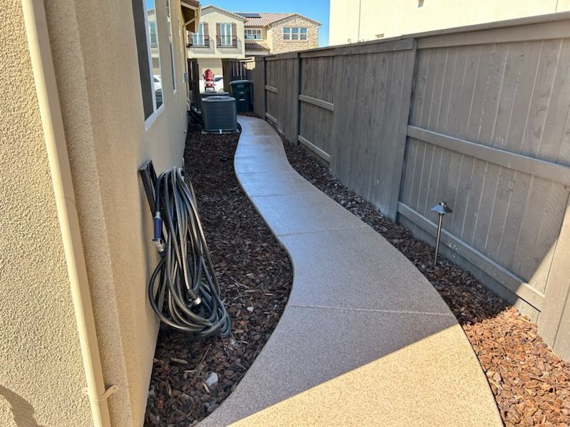 A hose is hanging on the side of a house next to a fence.