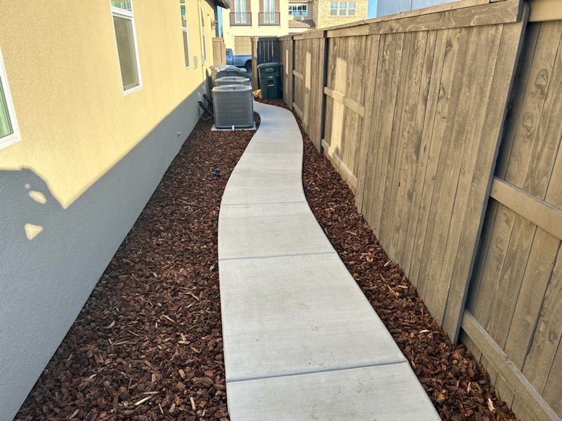 A concrete walkway leading to a wooden fence