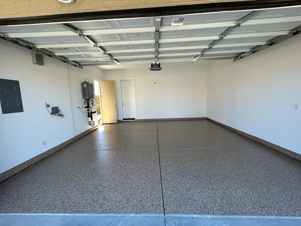 An empty garage with a garage door open and a ceiling fan.