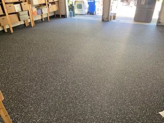 A garage with a gray floor and a ladder.