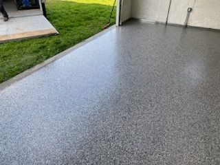 A gray concrete floor in a garage with grass in the background.