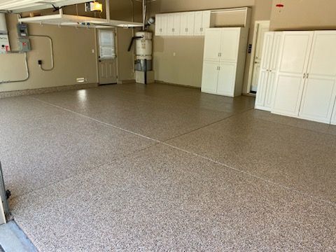 A garage with a concrete floor and white cabinets.