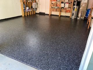 A garage with a black floor and a shelf with boxes on it.