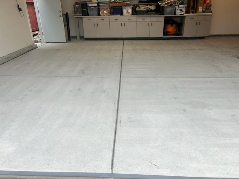 A concrete floor in a garage with cabinets and a sink.