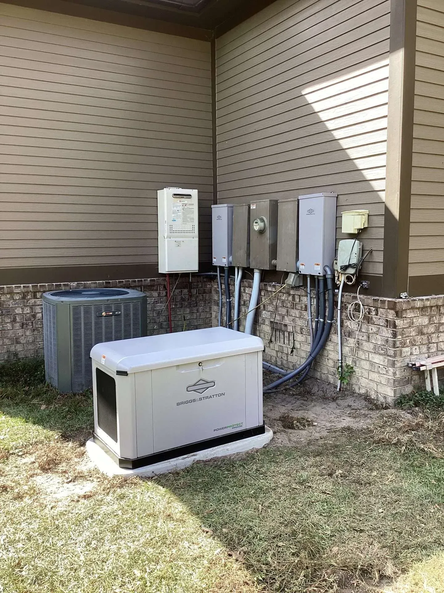 Outdoor utility equipment and electrical boxes mounted on a house wall beside an air-conditioning unit.