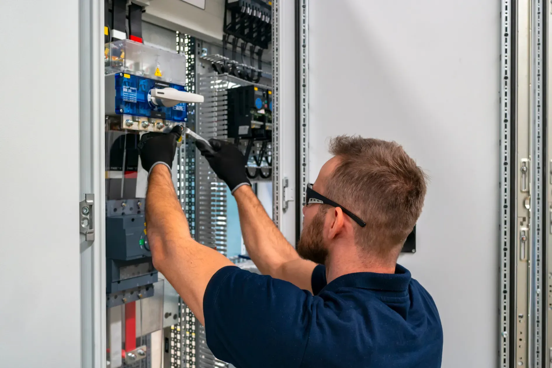 Technician wiring an electrical control panel inside an open cabinet