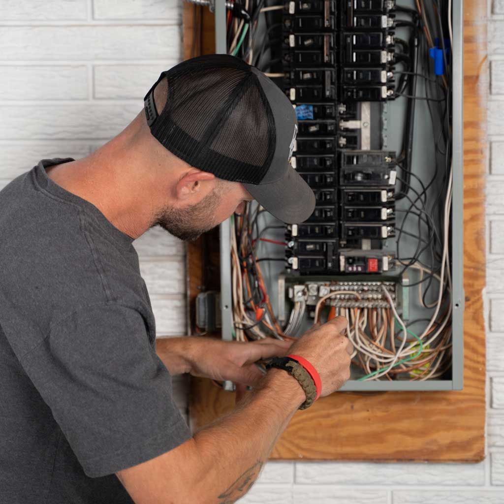 Technician wiring an electrical panel in a wall-mounted breaker box