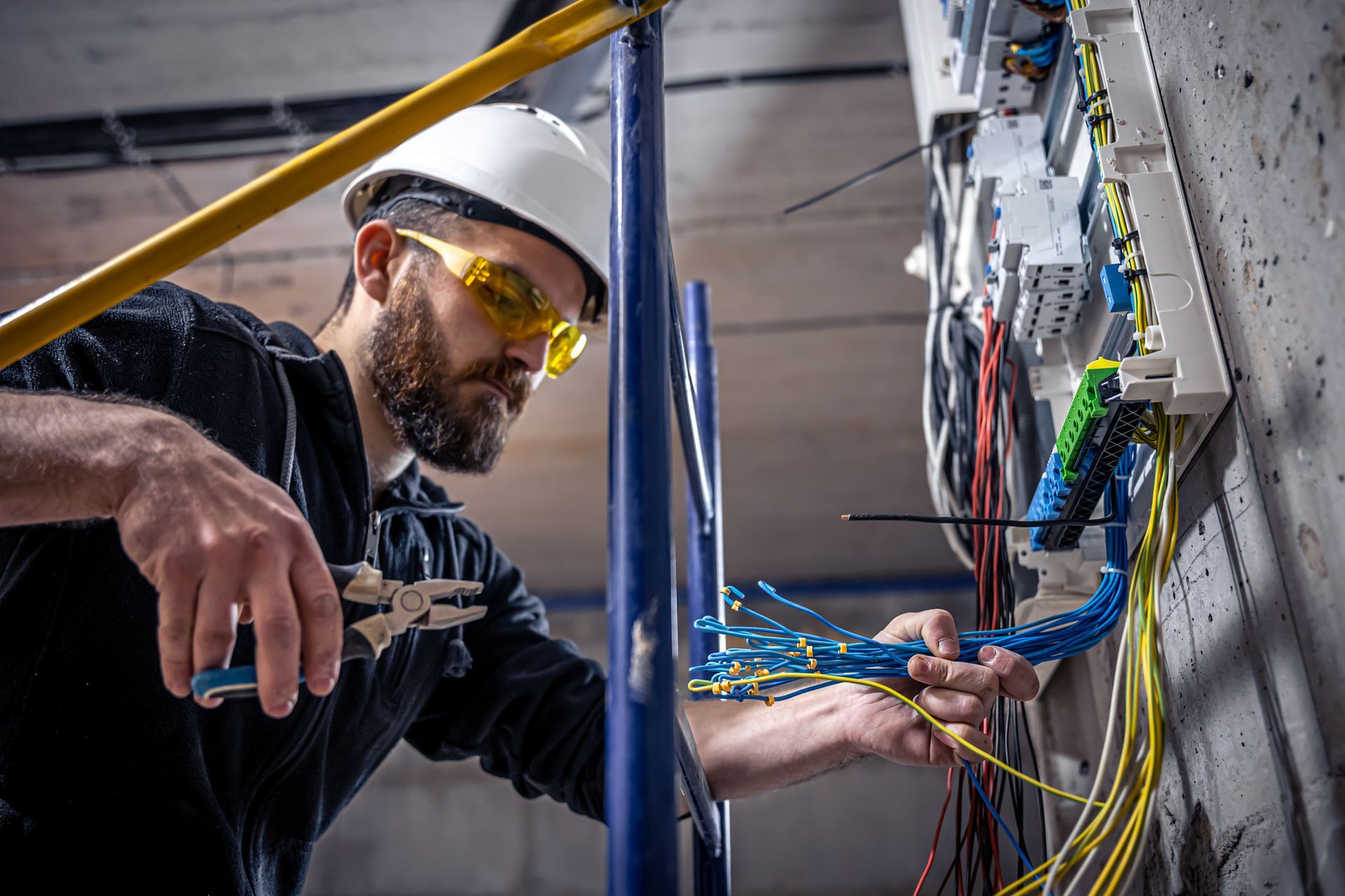 Electrician wiring a server rack, wearing a hard hat and safety glasses