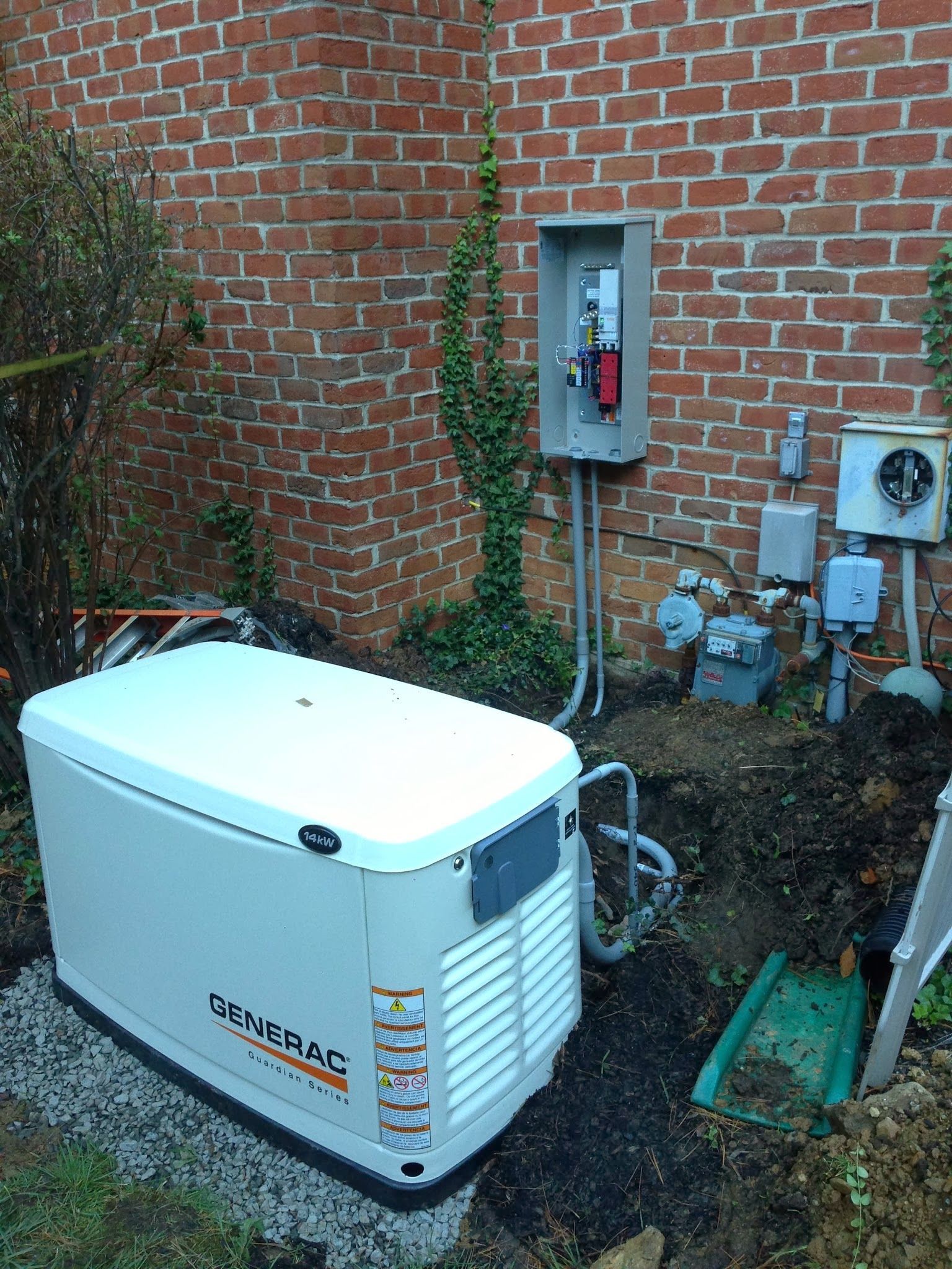 Portable generator beside brick house with electrical panel, pipes, and utility meters outdoors