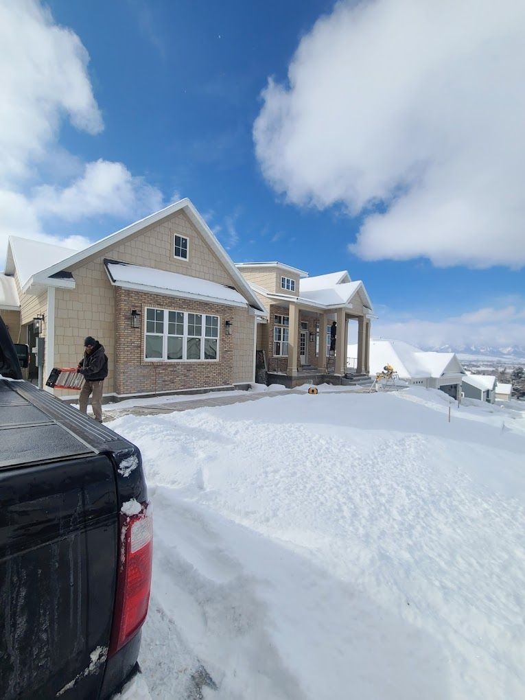 Snow-covered suburban house with a person near the driveway under a bright blue sky