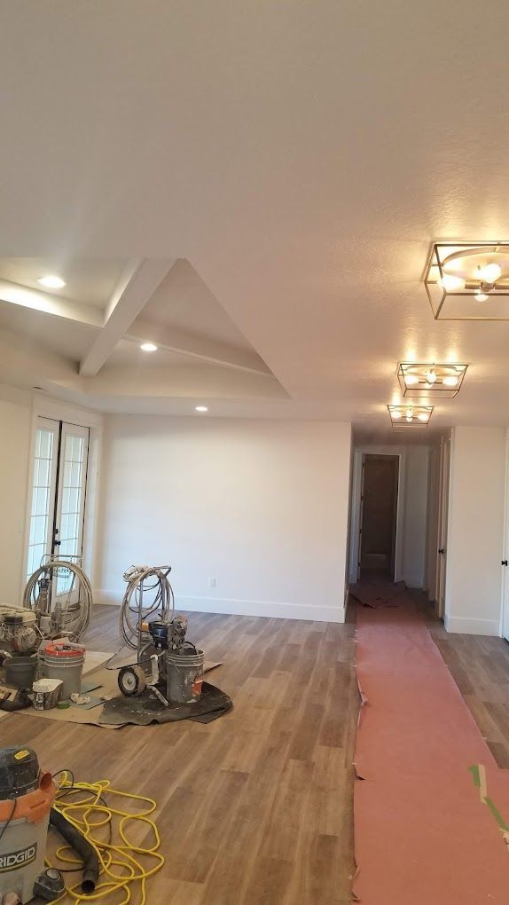 Renovated room with hardwood floors, white walls, ceiling lights, and construction tools on the floor