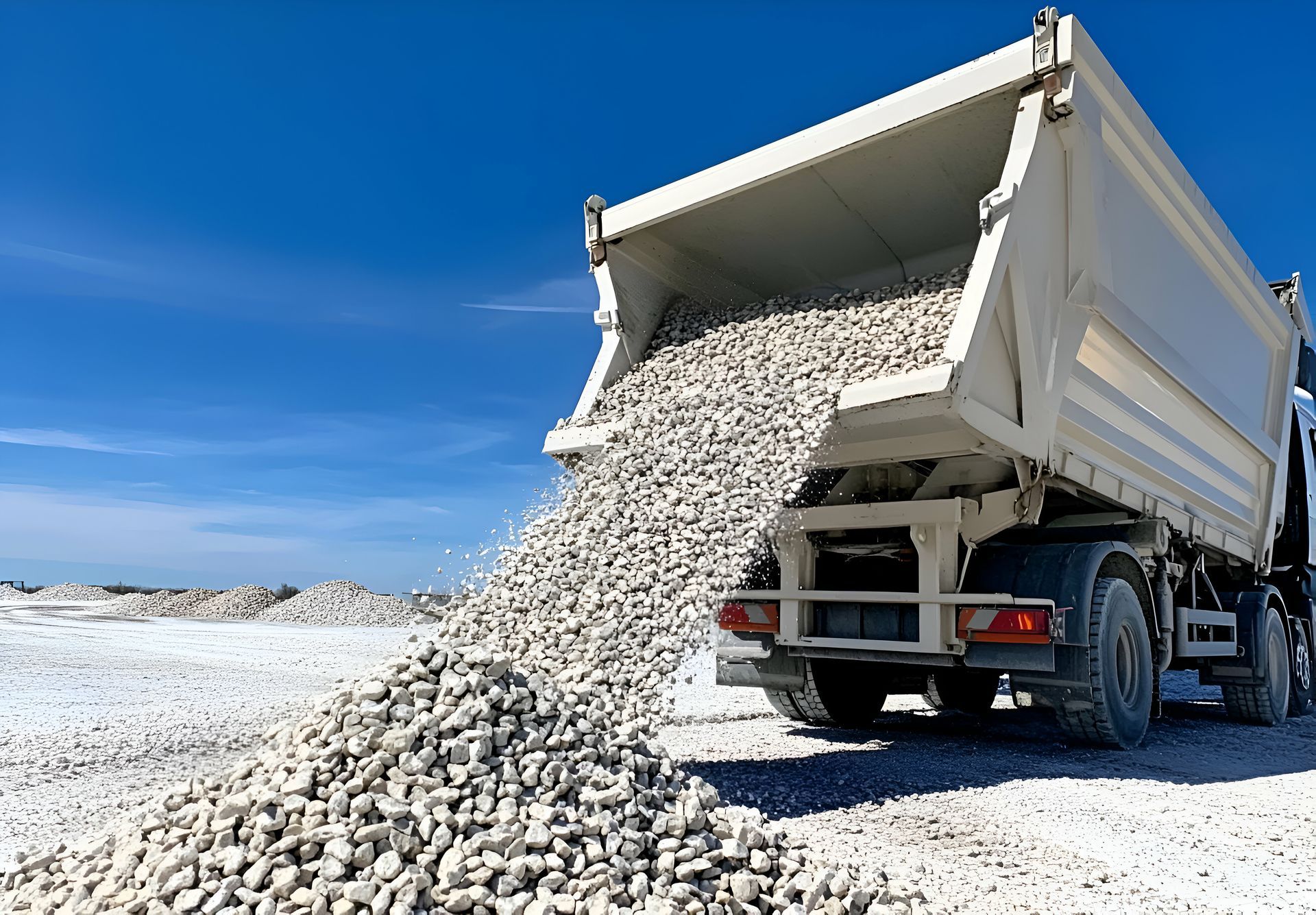 A dump truck is loading gravel into the back of it.