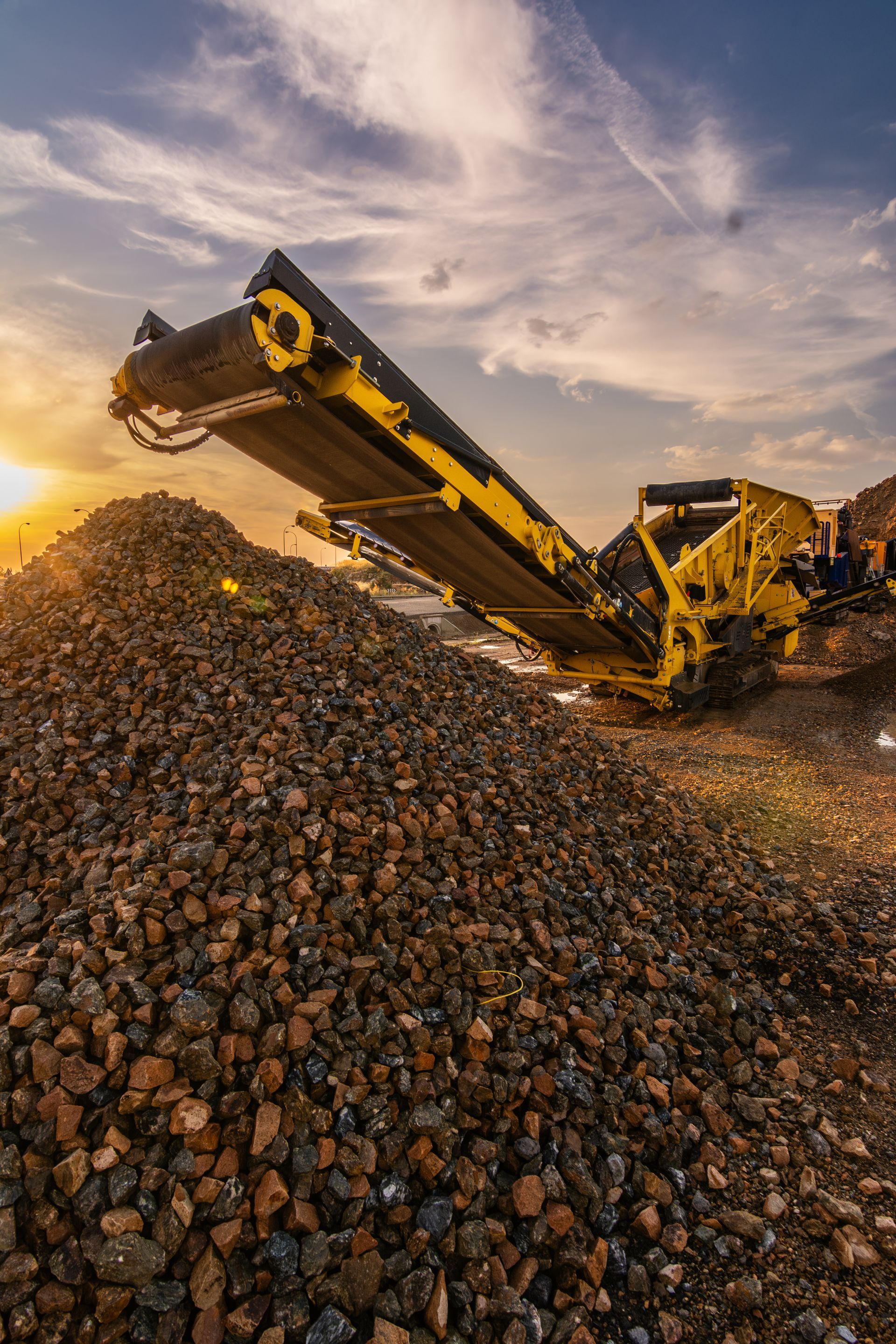 A yellow machine is sitting on top of a pile of rocks.