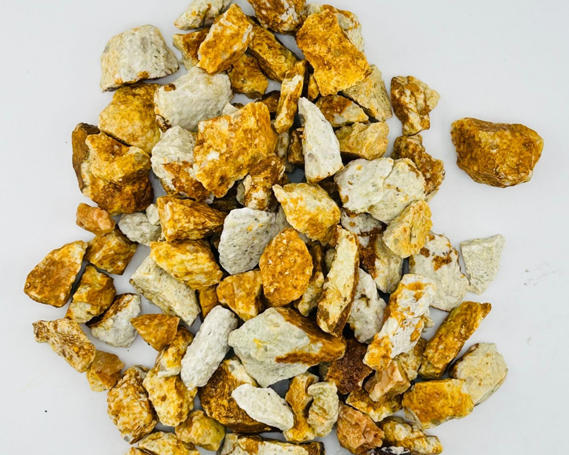 A pile of rocks of different sizes and colors on a gray surface.