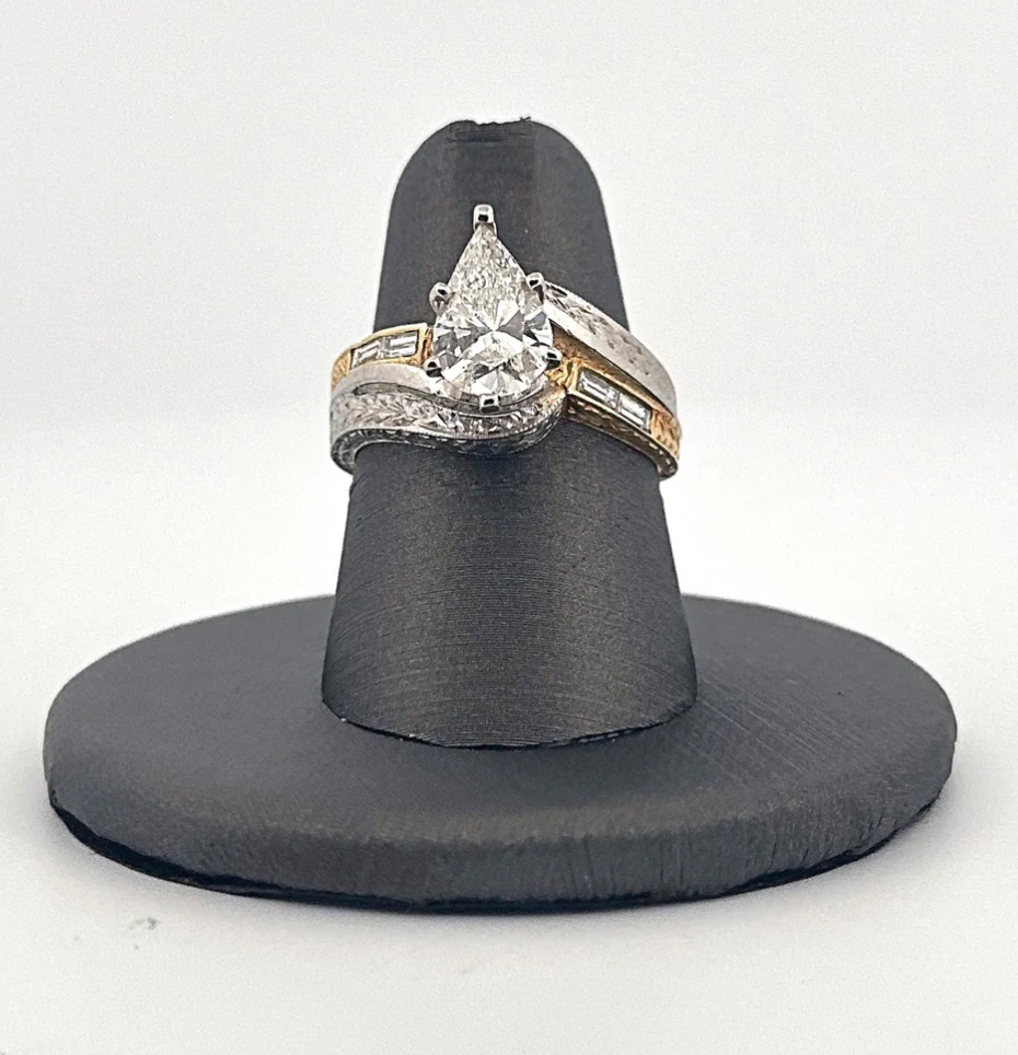 A pear shaped diamond ring is on a black ring holder