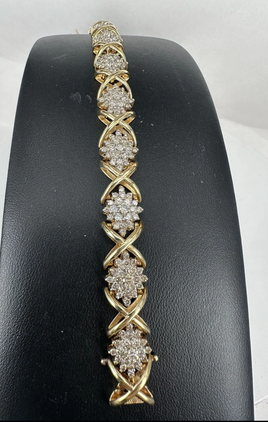 A gold bracelet with diamonds is on a black mannequin