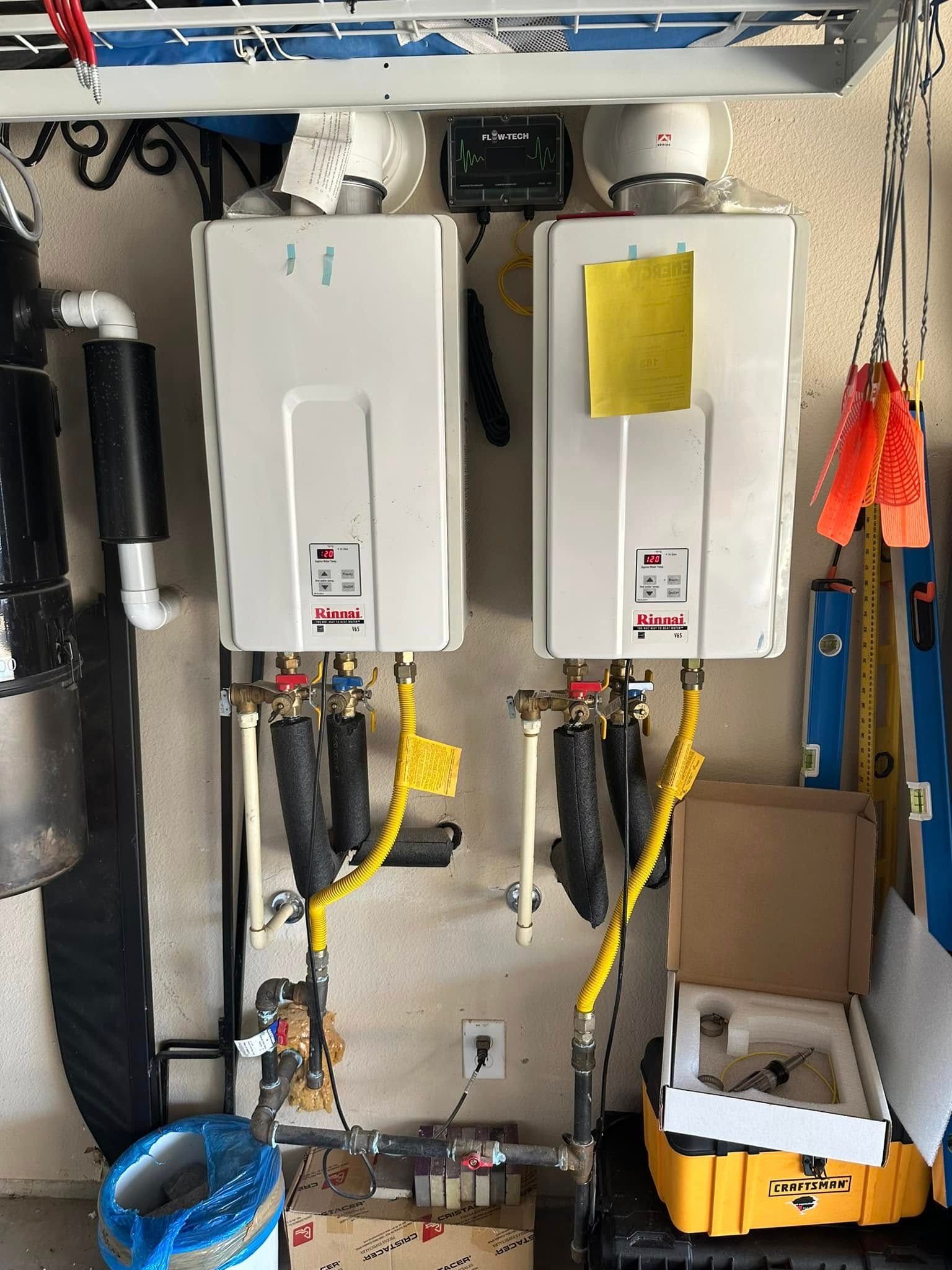 Two water heaters are hanging on a wall in a garage.
